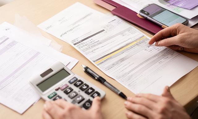 自宅のテーブルで通信費と保険料の明細を並べて見直す手元